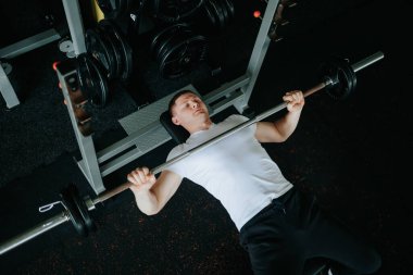 Halterle sıkı bir antrenman yapan aktif bir adam spor salonundaki fitness hedeflerine ulaşmak için limitlerini zorluyor. Fiziksel Fitness için Halterle Güç ve Hassas Yoğunluk Eğitimi