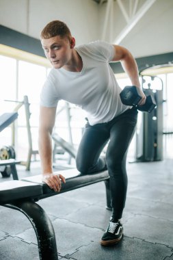 Kararlı bir adam spor salonunun bir parçası olarak ağırlık kaldırma egzersizi yapar. Kararlı bir adam halter kaldırma egzersizi yapıyor.,