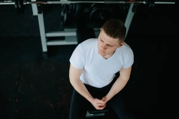 stock image Revitalizing Break A tired man takes a seat, finding tranquility and recovery after a challenging workout at the gym. calmness of the gym, a tired man finds solace and restores his energy after