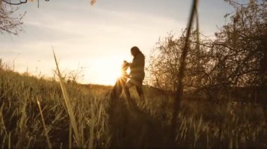 Kadın ve labradoru gün batımında doğanın güzelliğini kucaklıyor. Kadın, evcil köpekleriyle keyifli bir etkileşim içinde.