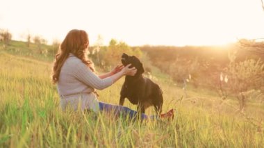 Kadınlar gün batımında köpekleriyle oynarken saf neşe. Güzel anlar. Kadın ve labradoru gün batımında dışarıda eğleniyorlar.