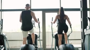 Hispanik bir adam ve Amerikalı bir kadın ortak çalışma rutinine girip karşılıklı motivasyon sağlıyorlar. Genç Fit Çift Spor Salonu 'nda Birlikte Antrenman Yapıyor