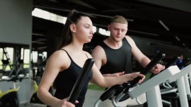 Motivasyonlu Spor Salonu Erkek Antrenörü genç bir kadının spor salonunda spor yapmasına ve fitness hedeflerine ulaşmasına yardım eder. Fitness İkili Erkek Antrenörü Spor Salonunda Genç Kadına Yardım Etti