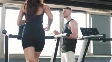 Genç bir çift, ikisi de Kafkasyalı, kişisel antrenörleriyle birlikte, aktif ve sağlıklı bir yaşam tarzını kucaklıyorlar. Dinamik Grup Çalışması Yöneten Kafkas Erkek Kişisel Eğitmeni