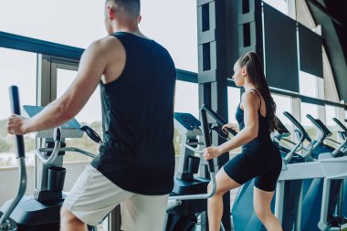 Hispanik bir adam ve Amerikalı bir kadın ortak çalışma rutinine girip karşılıklı motivasyon sağlıyorlar. Genç Fit Çift Spor Salonu 'nda Birlikte Antrenman Yapıyor