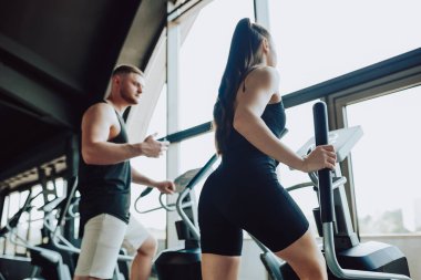 Yetenekli bir antrenör, spor salonunda güvenliğin ve verimliliğin önemini vurgulayan zorlu bir spor rutini sırasında bir bayan sporcuya formda ve teknikte bulunuyor..