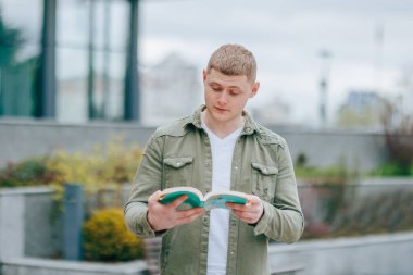 Dışarıda kitap okuyan bir adam, entrikaya kendini kaptırmış ve bunalmış. Açık havada neşeyle boğulmuş bir adamı okumanın mucizesi.