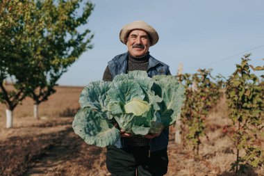 Kıdemli bir tarım uzmanıyla, deneyimin simgesi olan bıyığıyla, tarım arazisi yetiştirme sanatıyla uğraş. Ruhu yakalayan bir manzara.