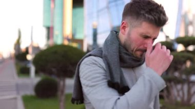 Genç adam öksürüyor, şehirde hapşırıyor. 