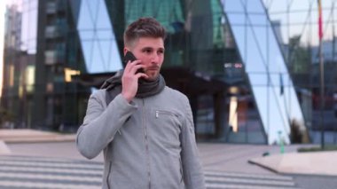 Genç adam akıllı telefon kullanıyor ve şehirde hapşırıyor.