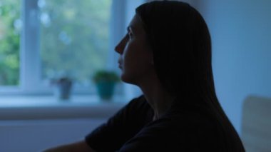 Yatak odasının karanlık sessizliğinde, genç bir kadın düşünceye dalmış yatağında oturuyor. Depresyon ve uykusuzluğun ezici ağırlığıyla savaşırken yüzü üzüntüyle dolu.