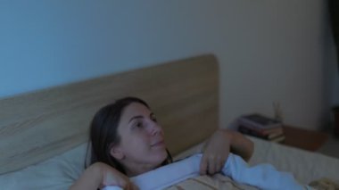 Yavaşça gülümseyen genç bir kadın rahat yatak odasında uyumaya hazırlanıyor. Gece onu sarıp sarmaladı. Yatmadan önce dinlendiği bir an..