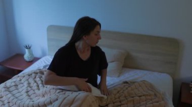 Nazik bir gülümsemesi olan genç bir kadın gece yatak odasında uyumaya hazırlanıyor. Sessiz ve rahat ortam, yatmaya hazırlanırken hissettiği huzuru yansıtıyor..