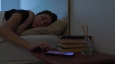 Akıllı telefon kullanımından yorulmuş ve bunalmış olan genç bir kadın cihazı bir kenara bırakıp yatağa uzanıyor ve sakin ve sessiz odasında uykuya dalmak için düzenli bir çaba sarfediyor..