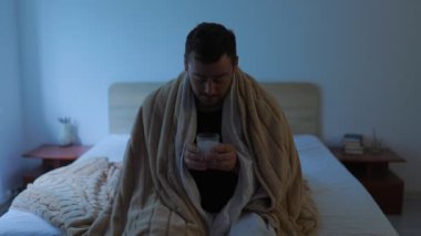 Ateşi olan bir kişi gece yatağında dinlenir, gözle görülür şekilde hasta ve bitkin. Yatak odası bir bardak su ve ilaç ile loş bir şekilde aydınlatılmış. Bu da mücadeleyi simgeliyor.