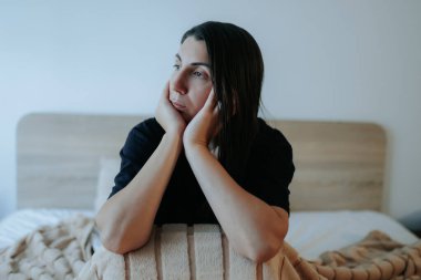 Gecenin sessizliğinde, genç bir kadın yatağında oturur, omuzları çaresizlik içinde kamburlaşır. Hissettiği yalnızlık ve depresyon üzgün ve uzak bakışlarında belli oluyor..