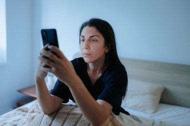 Geceleri yatakta uzanan bir kadın akıllı telefonunu kullanır, uyuyamaz. Karanlık oda onun uykusuzluğunu ve mobil cihazına olan bağımlılığını vurguluyor..
