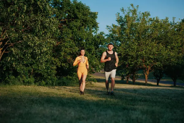 stock image A caucasian man, a professional personal trainer, provides guidance and support to a young female athlete, ensuring a productive and effective running workout in the great outdoors.