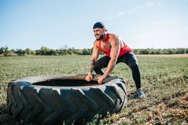Kaslı bir adam CrossFit tekerlek çekme eğitimine katılarak gücünü ve kararlılığını gösteriyor. Çapraz Fit Sporcusu Tekerlek Çekme Eğitimini Dışarda Gösteriyor