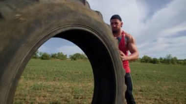Kaslı bir adam CrossFit tekerleğini dışarı çeker, gerçek bir sporcunun ruhunu somutlaştırır. Çapraz Fit Hevesli Açık Tekerlek Çekme Eğitimi