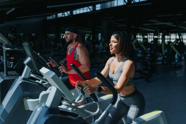 İki birey, bir erkek ve bir kadın, sıkı bir spor salonunda kas güçlerini gösteriyorlar, fitness 'in gücünü vurguluyorlar.