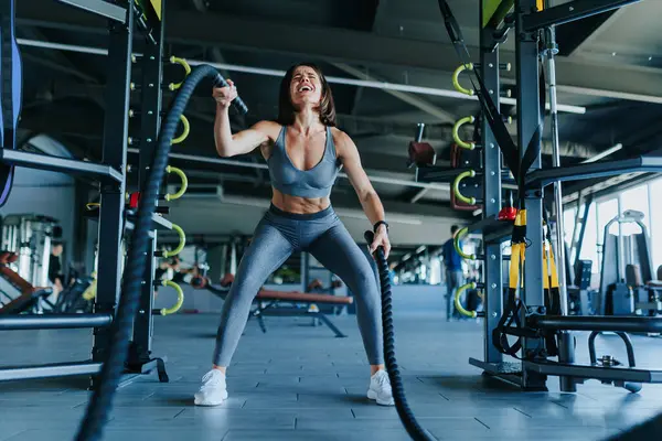 stock image In the gym, led by a determined young woman, focuses on their rope workout, illustrating their commitment to fitness. Determined Athletes Conquer Rope Workouts