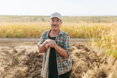 Tarım arazisinde bıyıklı yaşlı çiftçi, kırsal kesimin zengin deneyimini ve yaşam tarzını gösteriyor..