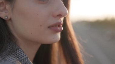 Gün batımının altın saatinde güzel bir esmer kadının portresi, cildi ışıl ışıl parlıyor ve ifadesi.