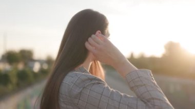Gün batımında açık havada esmer bir kadının sakin bir yakın çekimi. Sıcak ışık onun yumuşak, doğal güzelliğini yakalıyor..