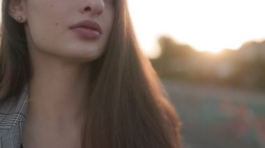 Güneşin son ışıklarıyla aydınlanan güzel, genç esmer kadın, gün batımında dışarıda çekilmiş portresi..