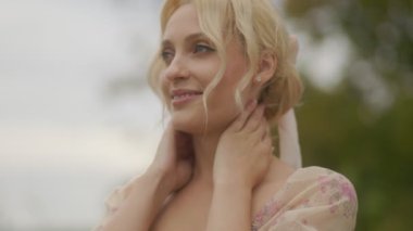 Neşeli, orta yaşlı, gülümseyen bir sarışın kadın. Gün ışığı yüzünü aydınlatıyor..