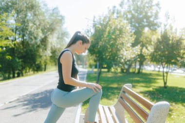 Esmer beyaz kadın, güneş ışığında parkta fiziksel egzersiz yapıyor. Formuna odaklandı, güzel bir günde dışarıda antrenman yaptı..