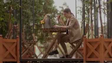 Sabah İş ve Muamelesi dizüstü bilgisayarında elinde kruvasan ve çay tutan mutlu esmer bir kadın güneşli bir terasta kahvaltı yapıyor..