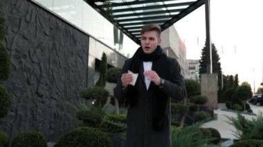 Açık havada mücadele eden genç bir adam grip belirtilerine katlanır, sürekli hapşırır ve öksürür, kentin dışındayken rahatsızlığı yansıtır..