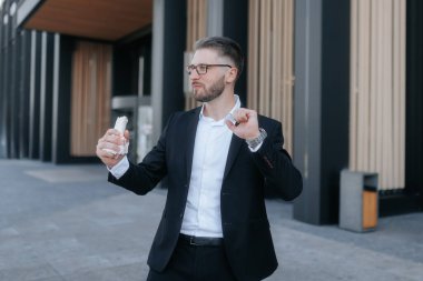 Takım elbiseli genç bir profesyonel şehir merkezindeki bir ofis binasının önünde sandviç yiyor..