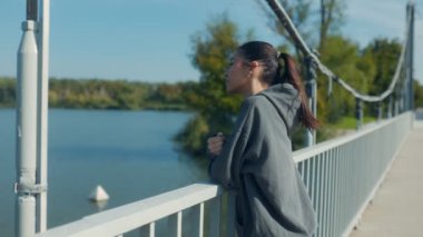 Parkta güneşli bir günde köprüde genç esmer bir kadın..