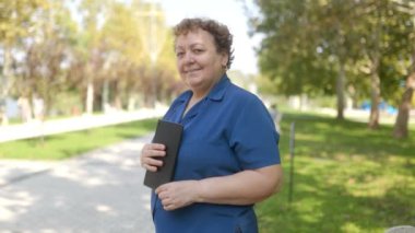 Açık hava ortamında tablet bilgisayarlı yaşlı bir kadının portresi.