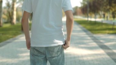 Beyaz tişörtlü genç bir çocuk parkta yürüyor. 