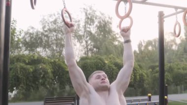  Erkek sporcu spor sahasında jimnastik halkaları kullanarak akrobatik jimnastik yapıyor. 