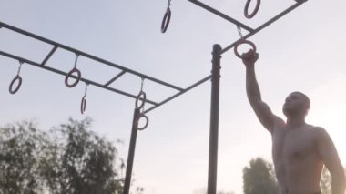  Erkek sporcu spor sahasında jimnastik halkaları kullanarak akrobatik jimnastik yapıyor. 