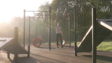  Erkek sporcu spor sahasında jimnastik halkaları kullanarak akrobatik jimnastik yapıyor. 