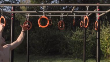  Erkek sporcu spor sahasında jimnastik halkaları kullanarak akrobatik jimnastik yapıyor. 