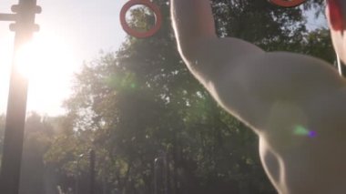  Erkek sporcu spor sahasında jimnastik halkaları kullanarak akrobatik jimnastik yapıyor. 