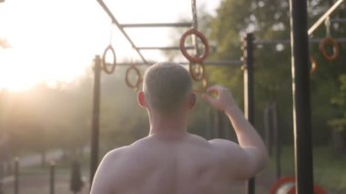  Erkek sporcu spor sahasında jimnastik halkaları kullanarak akrobatik jimnastik yapıyor. 