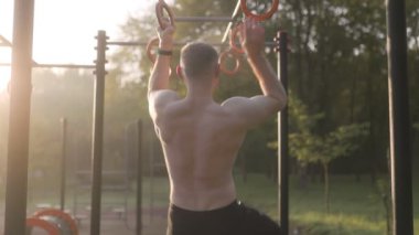  Erkek sporcu spor sahasında jimnastik halkaları kullanarak akrobatik jimnastik yapıyor. 