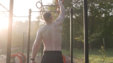  Erkek sporcu spor sahasında jimnastik halkaları kullanarak akrobatik jimnastik yapıyor. 