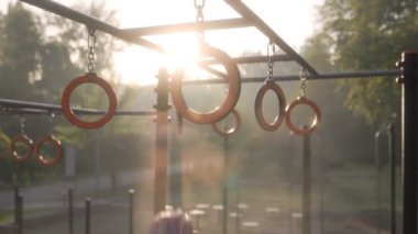  Erkek sporcu spor sahasında jimnastik halkaları kullanarak akrobatik jimnastik yapıyor. 