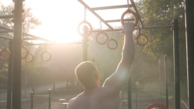  Erkek sporcu spor sahasında jimnastik halkaları kullanarak akrobatik jimnastik yapıyor. 