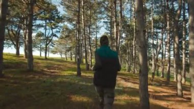 Kamuflaj yapan bir adam, ormanda koşar, arkadan yakalanır, sabah antrenmanı sırasında doğal ortamın ve temiz havanın tadını çıkarır..