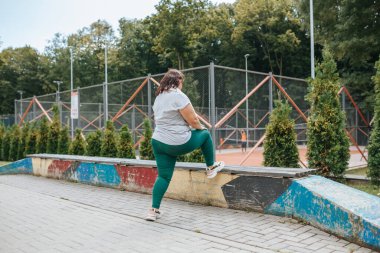 Sağlıklı bir yaşam tarzını benimseyen bu bayan, fazladan kilolarını vermek için çaba sarf ediyor. Açık hava fitness Aşırı kilolu kadının Daha Sağlıklı Bir Hayata Bağlılık